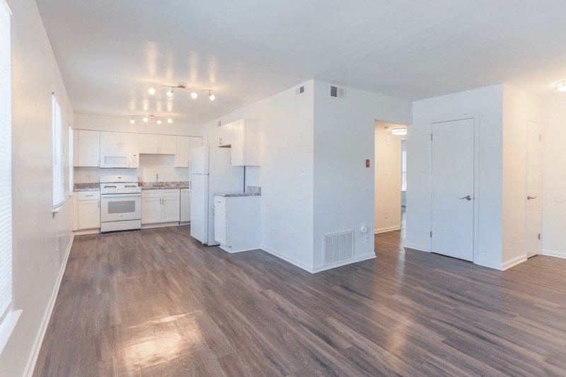 the living room and kitchen in a new home with white walls and wood flooring