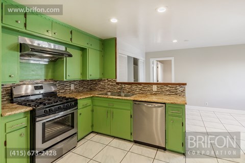 a kitchen with green cabinets and stainless steel appliances and a counter top
