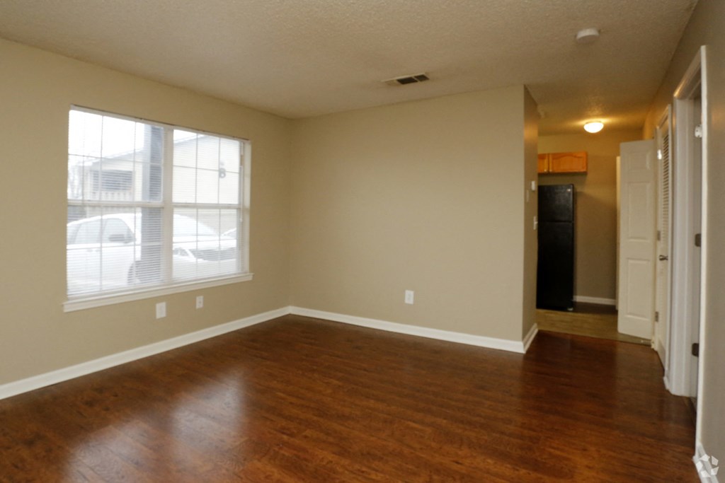 an empty living room with wood floors and a large window