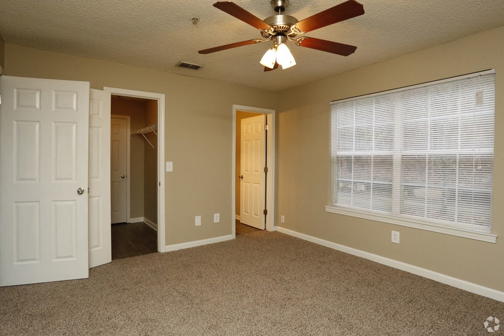 an empty living room with a ceiling fan and a window