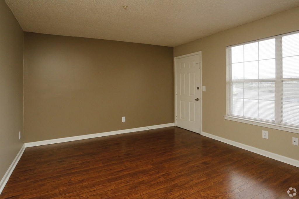 an empty living room with wood floors and a door