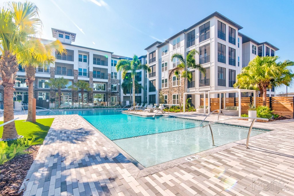 Resort-style pool with expansive sundeck and tanning shelf. Resort-style pool with expansive sundeck and pergolas at at Tapestry Nona Apartments in Orlando, FL