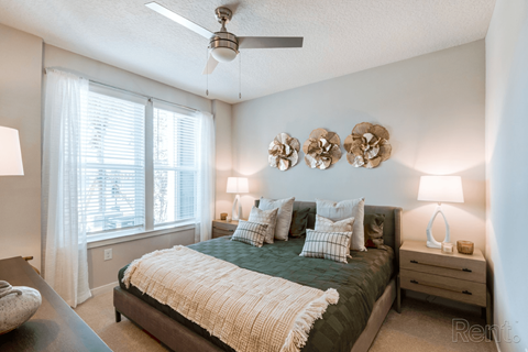 A bedroom with a bed, nightstand, and ceiling fan.