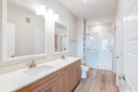 A white bathroom with a sink, mirrors, and a toilet.