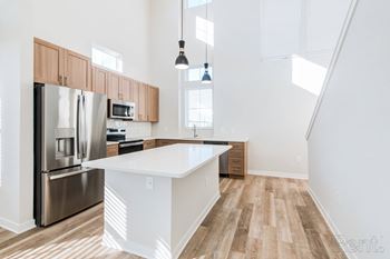 A kitchen with a white island and stainless steel appliances.