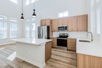Island kitchen with natural light, quartz countertops, and undermount sink at Tapestry Nona Apartments in Orlando, FL