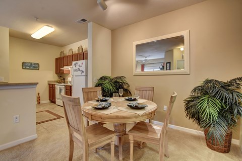 A dining room with a table set for two and a potted plant.