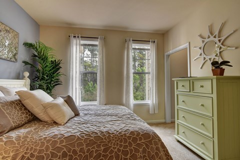 A bedroom with a large bed and a green dresser.