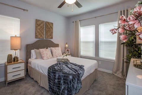 A bedroom with a bed, nightstand, and a ceiling fan.