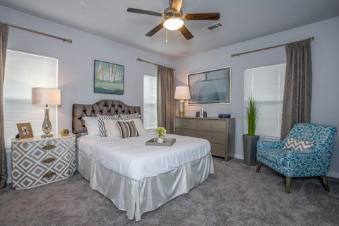 A bedroom with a bed, dresser, and chair.