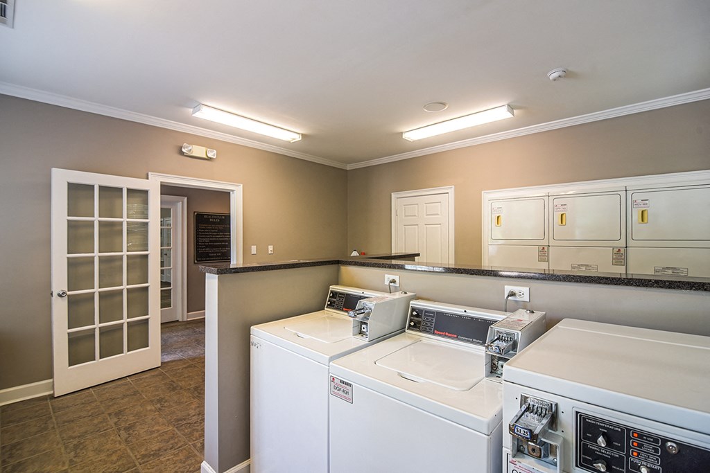 a laundry room with two washing machines and a door to a closet at 10X Audubon Park apartments in Daphne, AL 
