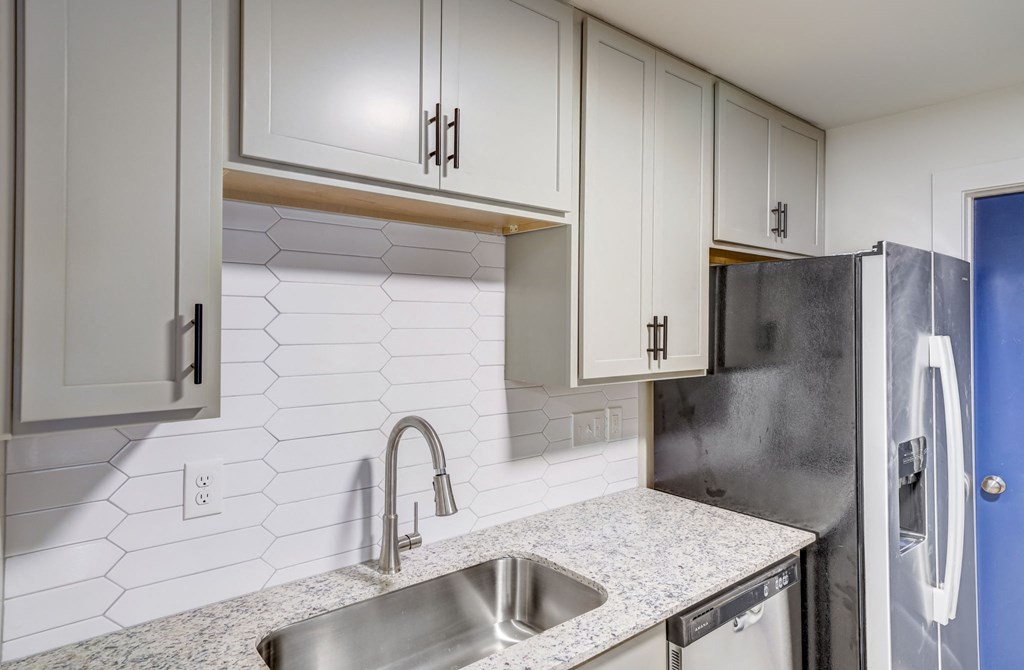 a white kitchen with white cabinets and a stainless steel sink