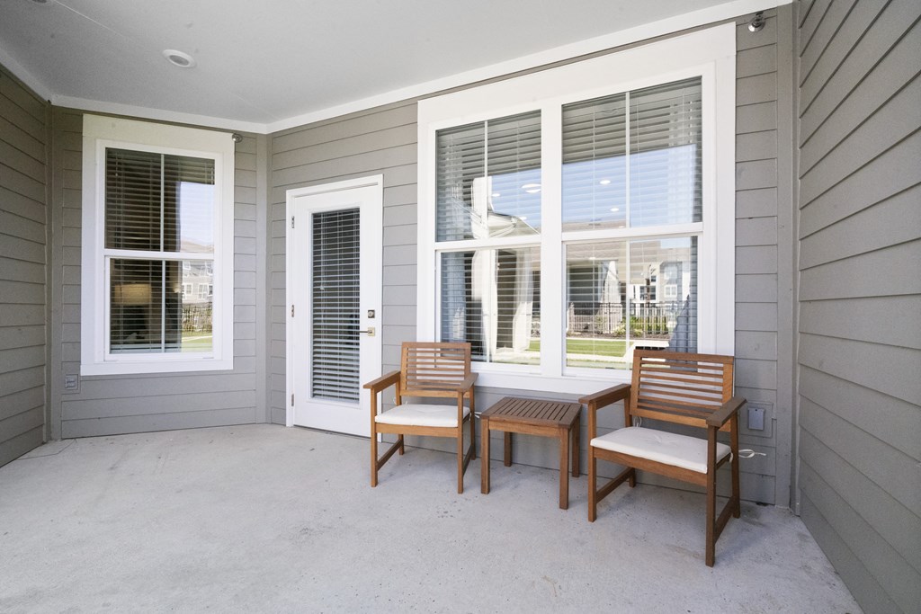 a patio with two chairs and a table and a door
