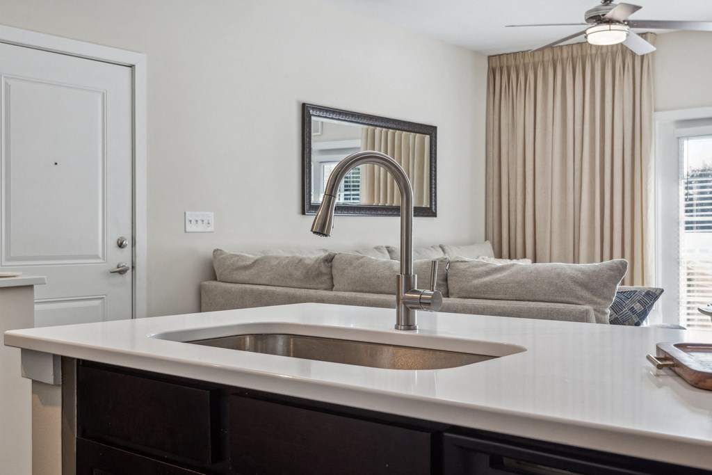 a kitchen counter with a sink and a living room with a couch at Hampton Roads Crossing, Suffolk, VA, 23435