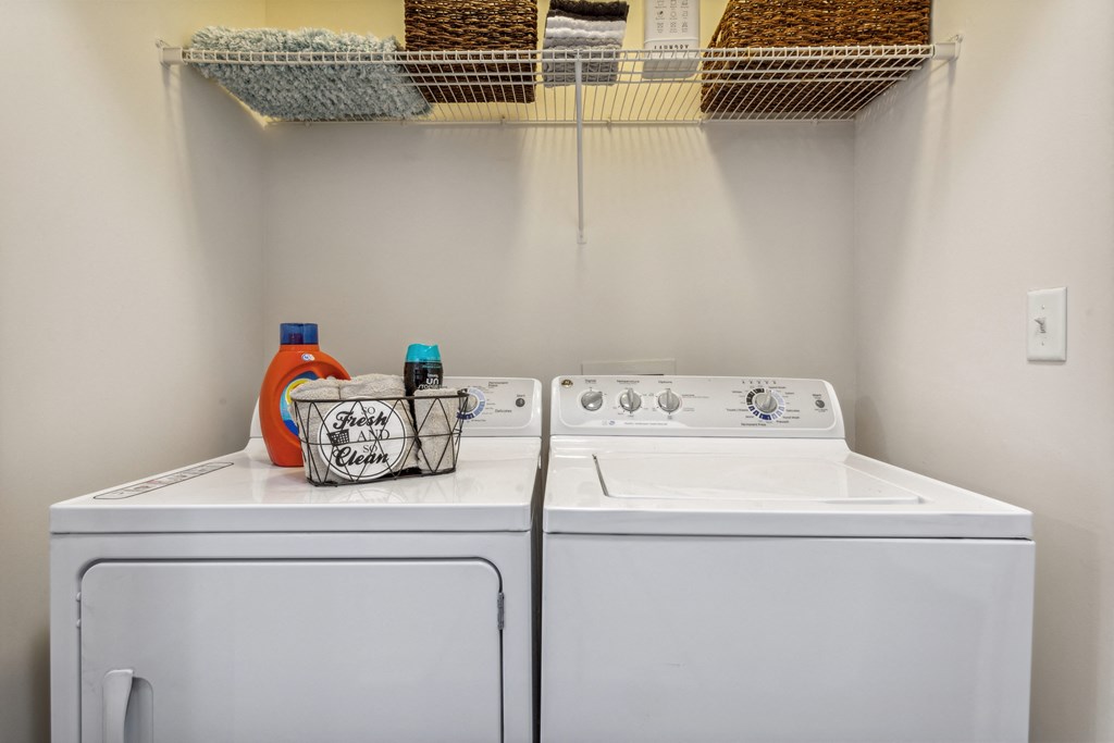 a washer and dryer in a laundry room with a shelf over the top at Hampton Roads Crossing, Suffolk, 23435