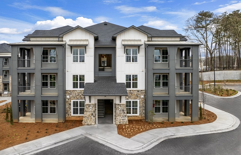 an exterior view of new apartments and large parking lot at Tapestry Overbrook in McDonough, Georgia