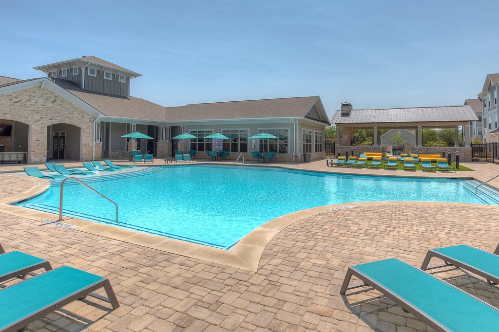 a resort style pool with lounge chairs and umbrellas