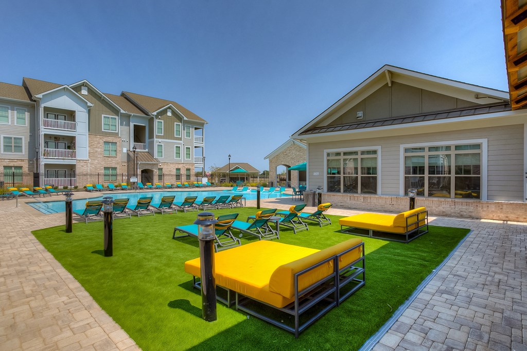 a resort style pool with lounge chairs and grassy area