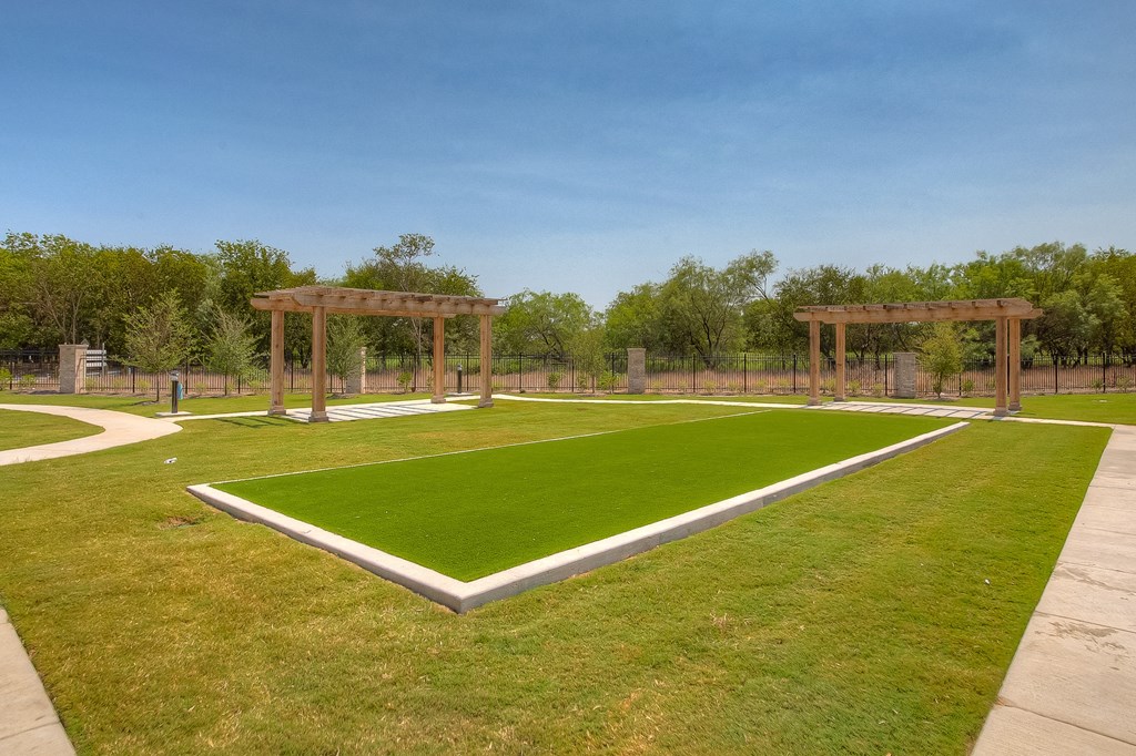 a grassy area with two pergolas in the background