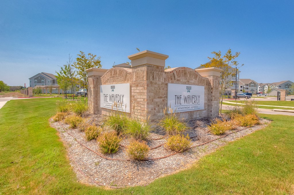 a stone monument with a sign that reads the winery in front of a grassy area