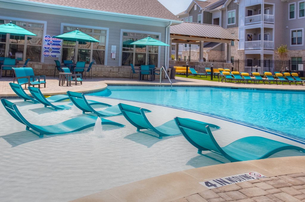 a swimming pool with blue chaise lounge chairs and umbrellas