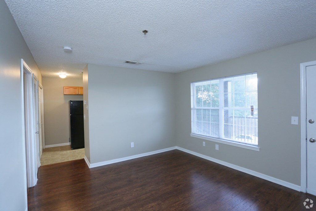 an empty living room with wood floors and a large window