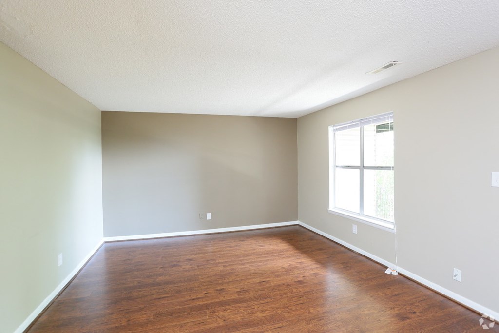 an empty room with wood floors and a window