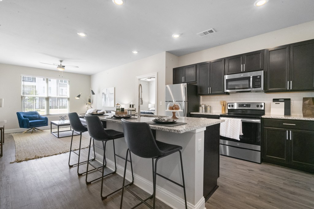 an open kitchen and living room with an island with bar stools