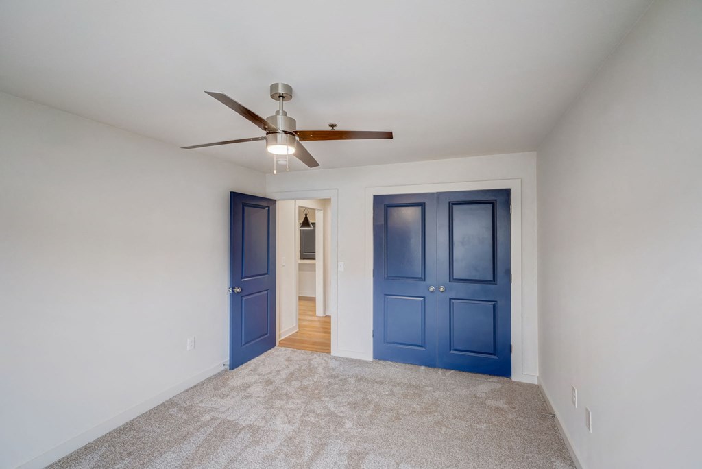 a empty room with blue doors and a ceiling fan