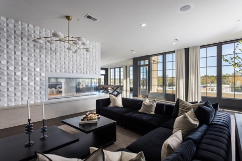 A modern living room with a black sofa and a white geometric wall.