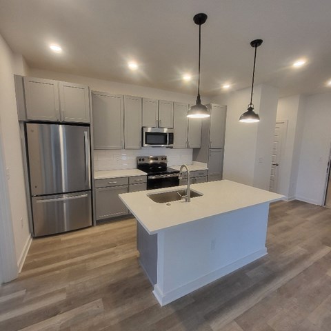 A kitchen with a white island and stainless steel appliances.