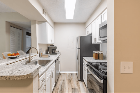 A kitchen with a black refrigerator and white cabinets.