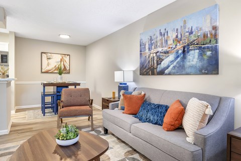 A living room with a grey couch, a coffee table, and a painting of a cityscape on the wall.