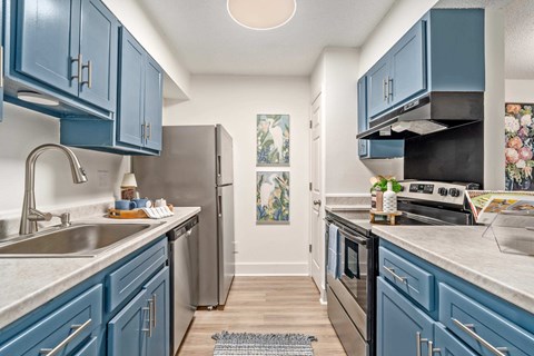 A kitchen with blue cabinets and a stainless steel refrigerator.