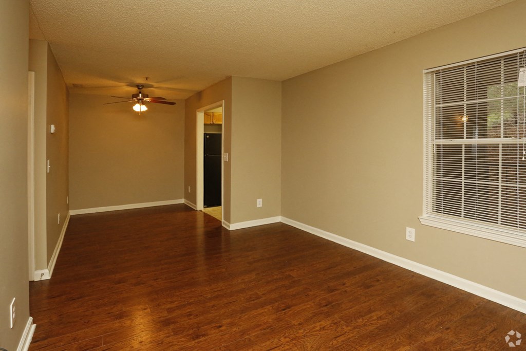 an empty living room with a ceiling fan and a window