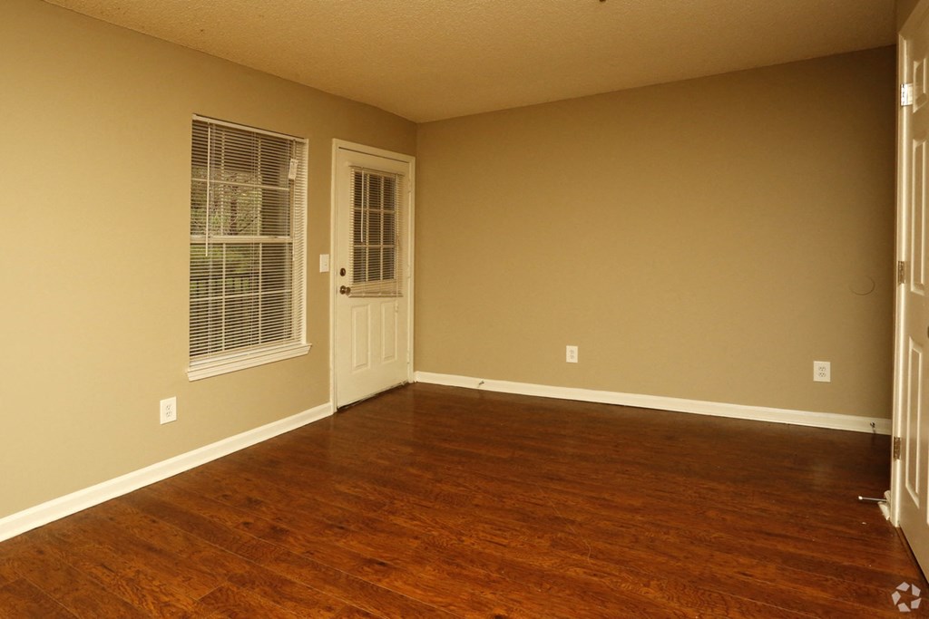 an empty living room with wooden floors and a door