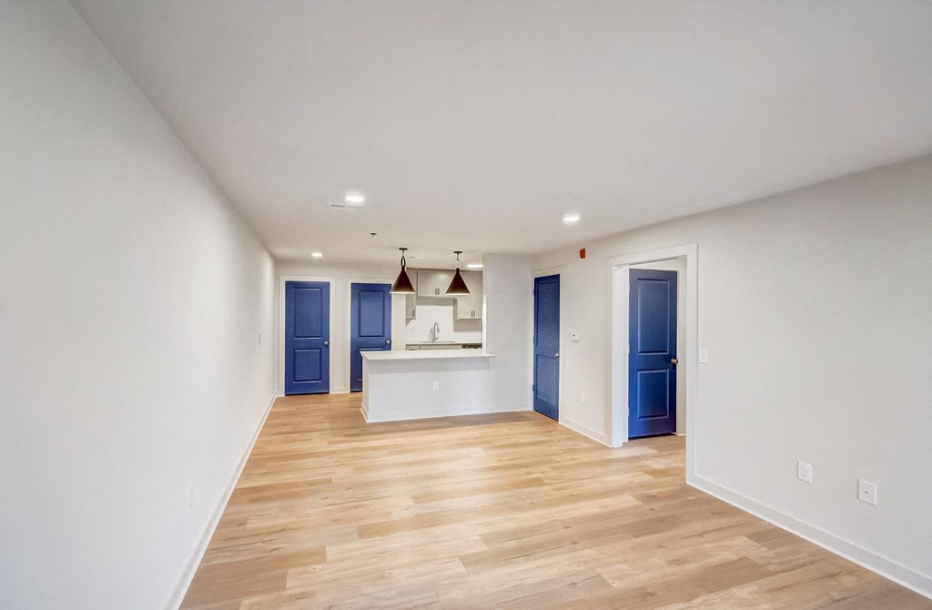 a living room and kitchen with white walls and wood flooring