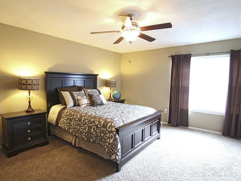 A bedroom with a large bed and a ceiling fan at The Oakley at Hillcrest in Mobile, AL