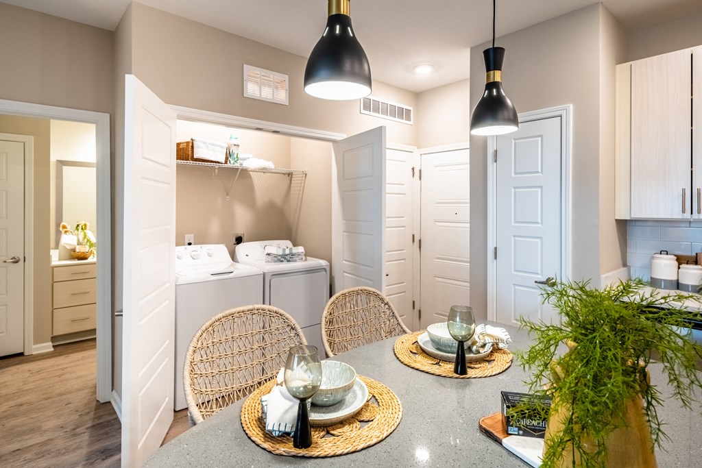 a dining area with a table and chairs and a kitchen with a washer and dryer