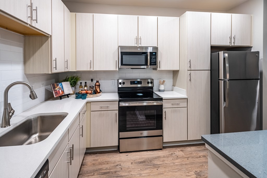 kitchen with white cabinets and stainless steel appliances at the enclave at woodbridge apartments in sugar land