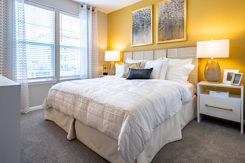 a bedroom with yellow walls and a large bed with a white comforter