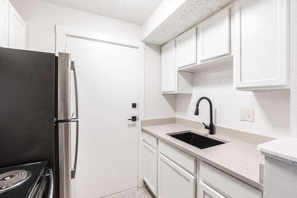 a kitchen with white cabinets and a black refrigerator