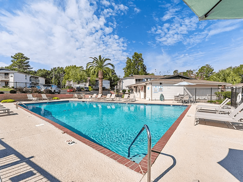 A large swimming pool with a metal ladder and a red brick border.
