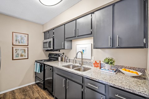 A kitchen with black cabinets and a white sink.
