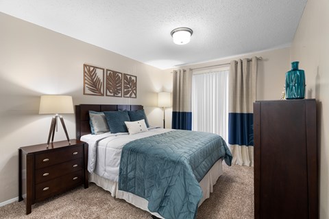 A bedroom with a bed, nightstand, and lamp.