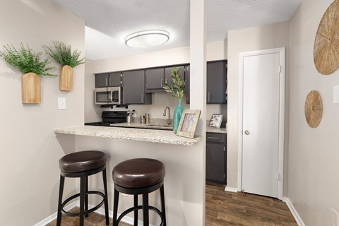 A kitchen with a white countertop and brown stools.