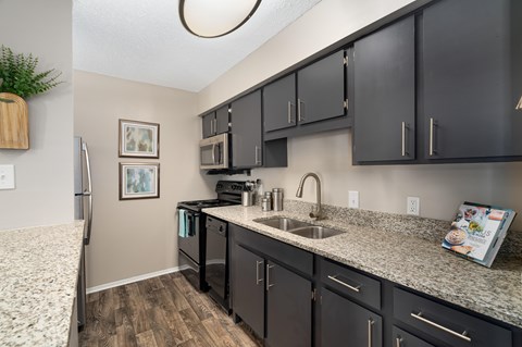 A kitchen with black cabinets and a granite countertop.