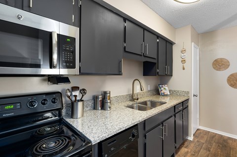 A kitchen with black cabinets and a stove top oven.