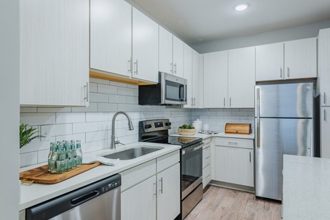 an all white kitchen with stainless steel appliances and white cabinets