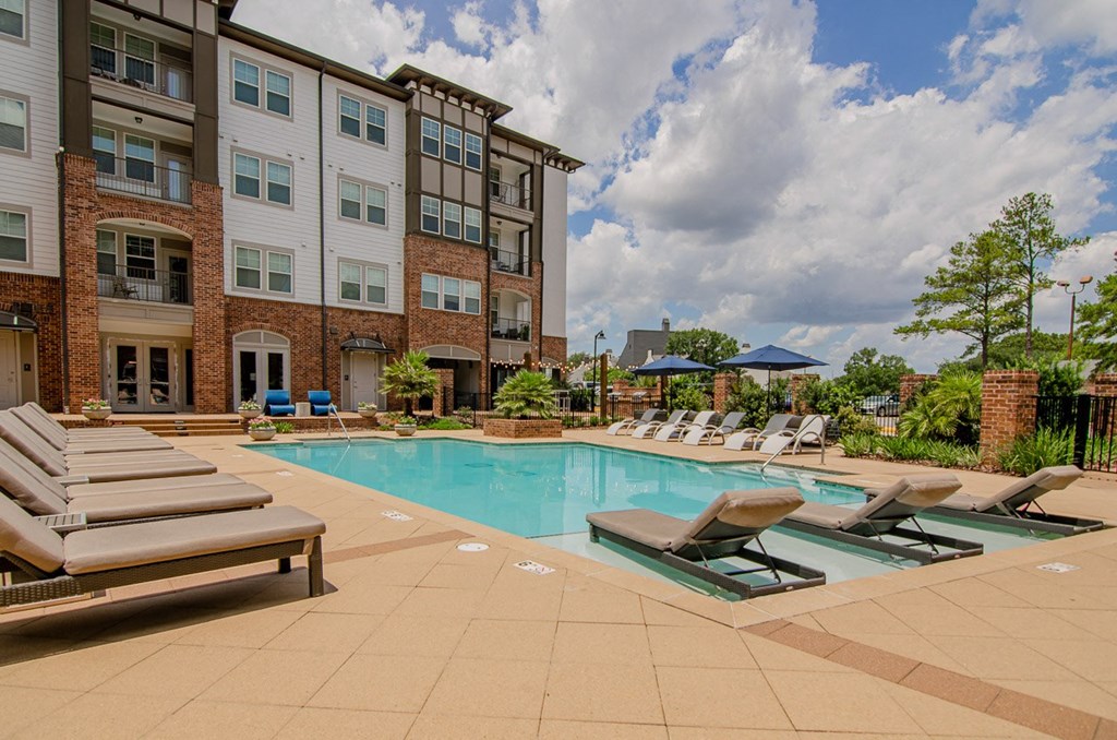 a swimming pool with lounge chairs in front of an apartment building